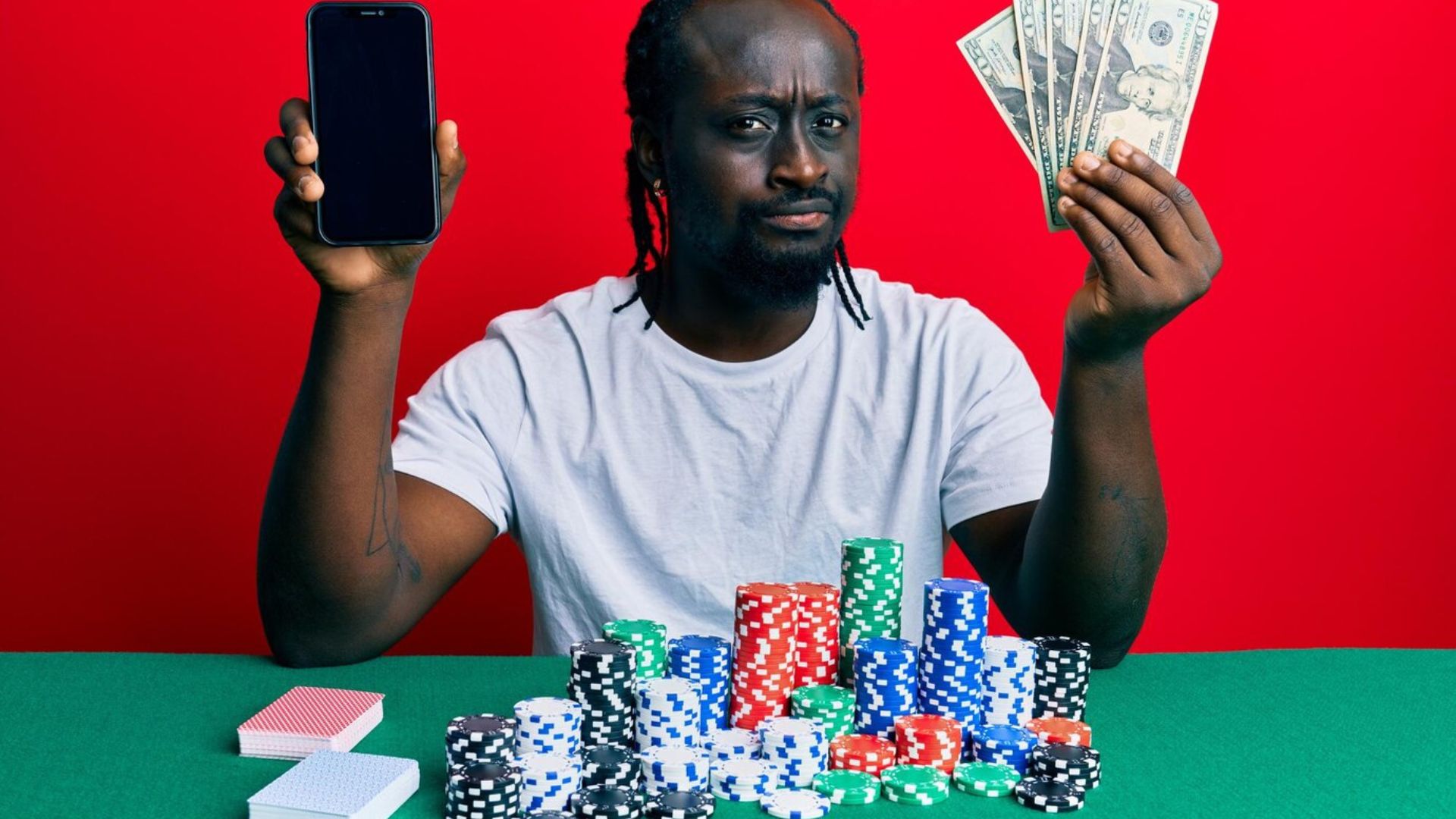 a black man holding a phone and playing cards showing the best online pokies in Australia